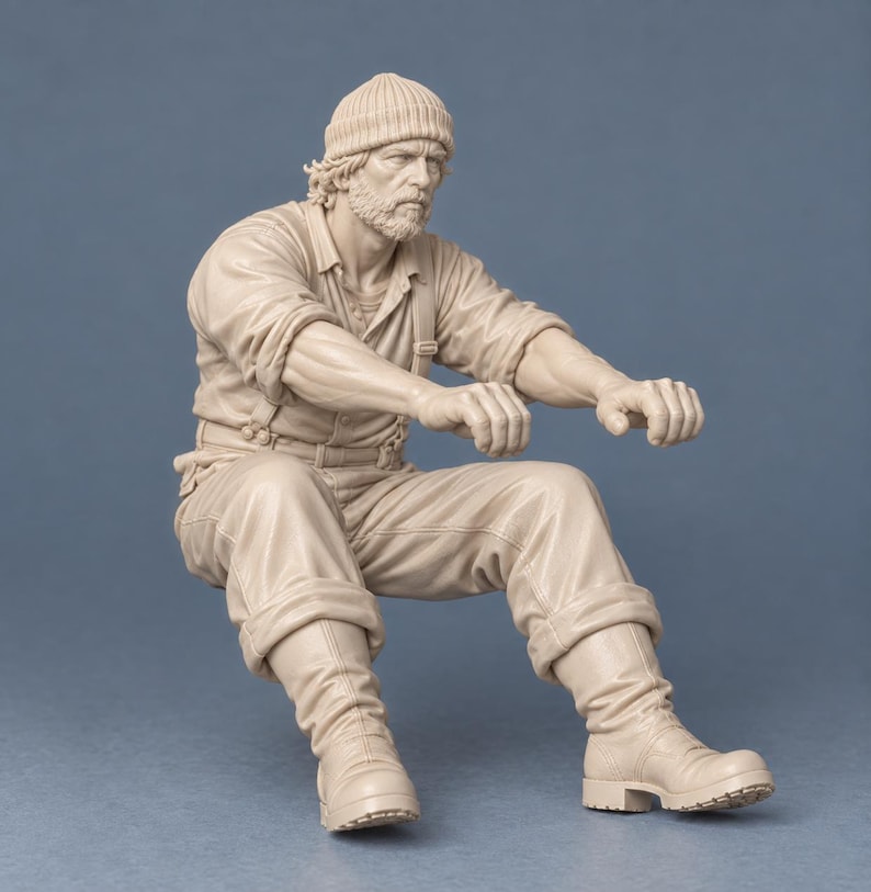 Puede incluir: Una figura a escala de color beige monocrom&aacute;tico que representa a una persona barbuda con gorro de punto, camisa de cuello con mangas remangadas, tirantes, pantalones y botas pesadas, en posici&oacute;n sentada con los brazos extendidos.