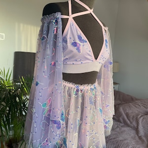 May include: A lavender-colored two-piece outfit with butterfly embellishments. The top is a halter style with a mesh fabric and the skirt is a tulle skirt with a ruffled hem.