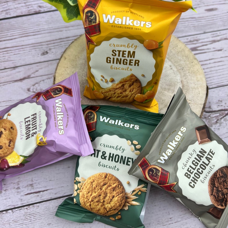 May include: Four packets of Walkers biscuits. The yellow packet features Stem Ginger, the purple packet features Fruit & Lemon, the dark green packet features Oat & Honey, and the grey packet features Chunky Belgian Chocolate. Each packet displays the brand name.