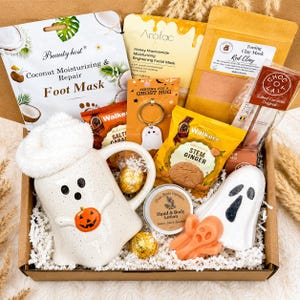 May include: A gift box containing a white ghost-shaped mug with a pumpkin, a ghost keychain, a ghost-shaped bath bomb, a ghost-shaped soap, a jar of lotion, a coconut foot mask, a honey facial mask, red clay mask, stem ginger biscuits, and chocolate.