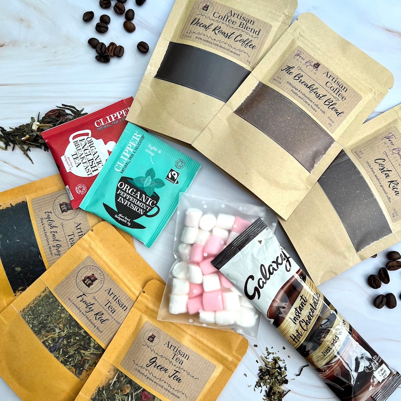 May include: Assortment of tea and coffee bags in brown paper packaging with labels. The labels include the names of the different types of tea and coffee, such as "English Earl Grey", "Fruity Red", "Green Tea", "Decaf Roast Coffee", "The Breakfast Blend", and "Costa Rica". There are also two bags of Clipper brand organic tea, one with peppermint infusion and one with English breakfast tea. A bag of marshmallows and a Galaxy hot chocolate packet are also included.