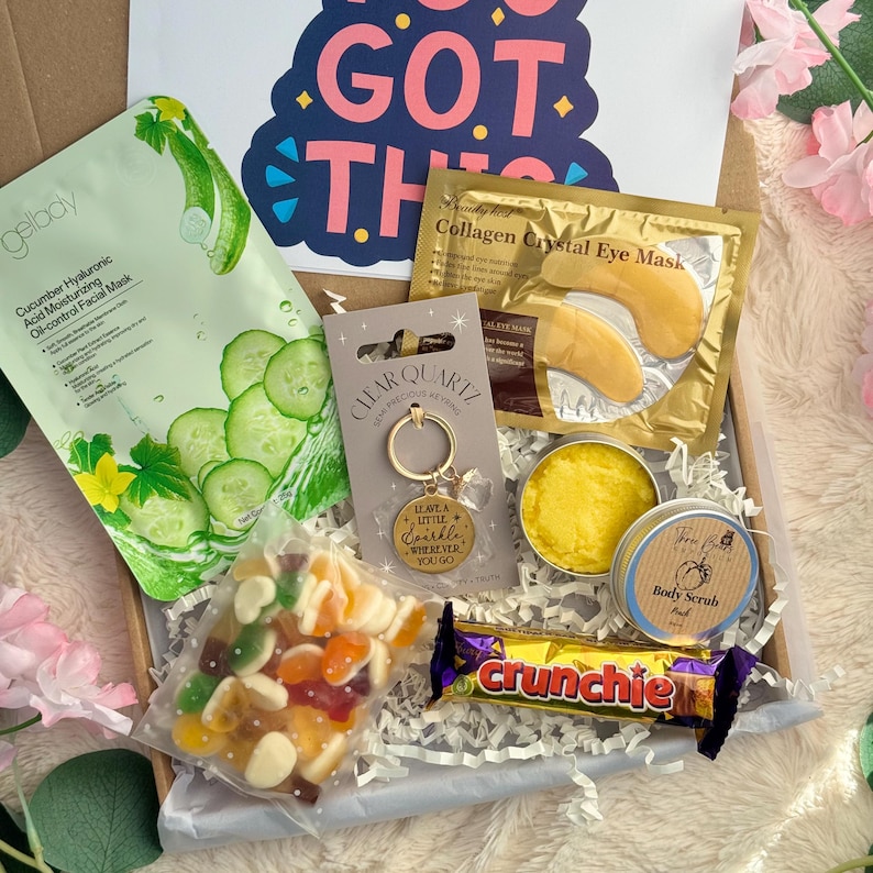 May include: A gift box filled with self-care items. Includes a cucumber facial mask, eye masks, a keychain with the text "Leave a little sparkle wherever you go", body scrub, candy, and a Crunchie candy bar.