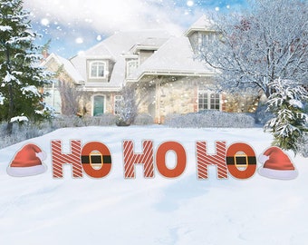Könnte beinhalten: Roter und weißer gestreifter Garten-Schilder mit den Worten "HO HO HO" und zwei Weihnachtsmützen an beiden Enden. Das Schild steht vor einem Haus mit einem schneebedeckten Rasen.