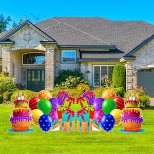 May include: A birthday party yard sign set with two large cake centerpieces, colorful balloons, and gift boxes. The sign set is displayed in front of a house.