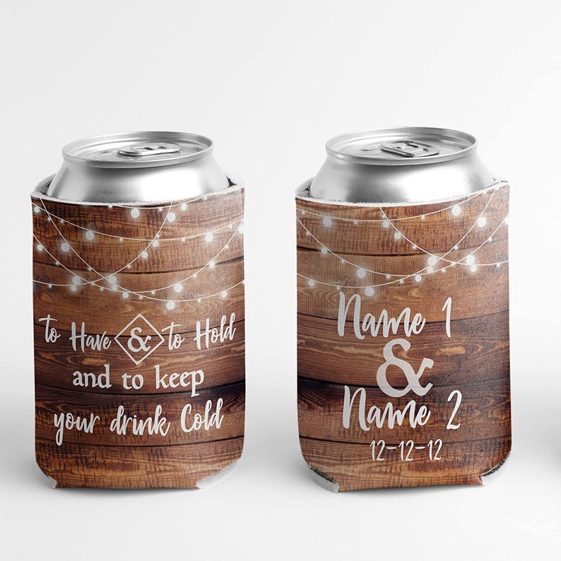 Op de afbeelding: Twee rustieke bruine houten blikjeskoelers met witte lichtslingers en witte tekst. Een koeler zegt "To Have & to Hold and to keep your drink Cold". De andere koeler zegt "Name 1 & Name 2 12-12-12".