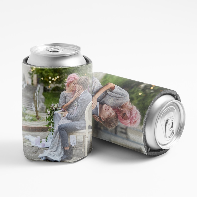 Może przedstawiać: Biały ochładzacz do puszek z fotografią pary w ogrodzie. Para siedzi na ławce, kobieta w r&oacute;żowej sukience, a mężczyzna w szarym garniturze. Tło to zielony ogr&oacute;d z lampkami.