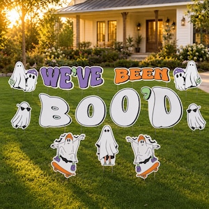 May include: A set of yard signs featuring the text WE'VE BEEN BOO'D in purple and orange lettering, accompanied by various ghost illustrations including ghosts wearing hats, sunglasses, and ghosts riding skateboards on a green lawn.