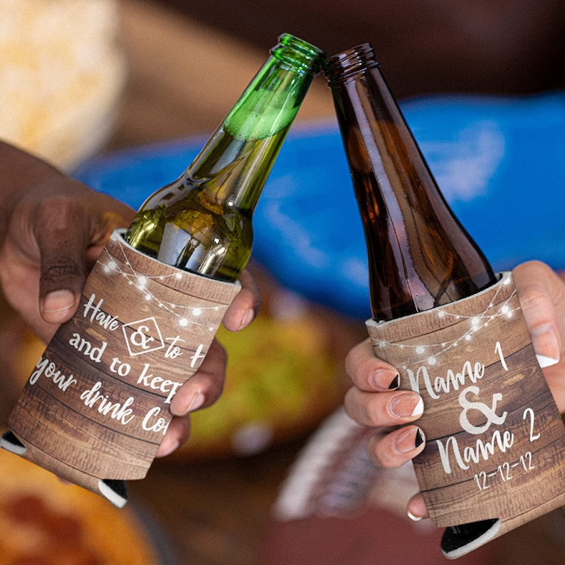 Op de afbeelding: Twee bruine en witte ge&iuml;soleerde drankenhouders met een rustiek houtnerfpatroon. De ene houder heeft de tekst "Have & to t and to keep your drink Co" en de andere heeft de tekst "Name 1 & Name 2 12-12-12".