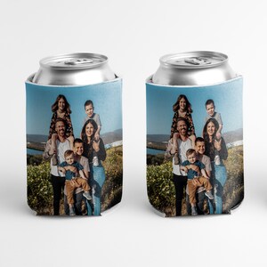 K&ouml;nnte beinhalten: Zwei blaue und wei&szlig;e Getr&auml;nkedosenk&uuml;hler mit einem Foto einer siebenk&ouml;pfigen Familie, die auf einem Feld steht. Die Familie l&auml;chelt und das Foto ist von der Taille aufgenommen.