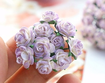 May include: A bunch of small, white paper roses with purple accents. The roses are arranged in a cluster and have a delicate, vintage look.