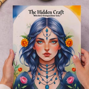 May include: A book cover titled "The Hidden Craft: Witches Companion Vol. 1" featuring a portrait of a woman with blue hair, adorned with floral and jewel accents. The cover art includes text about witchcraft and history.