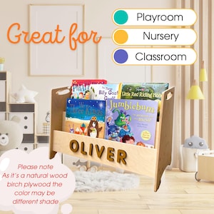 May include: A light wood children's book shelf with a personalized name "OLIVER" on the front. The shelf is filled with colorful children's books. The shelf is great for a playroom, nursery, or classroom.