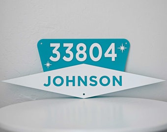 May include: A teal blue and white house number sign with the number 33804 and the name JOHNSON in white letters.