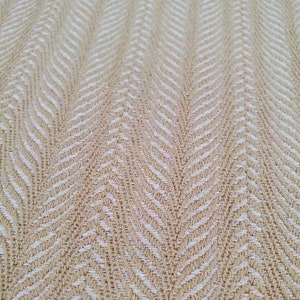 Può includere: Tessuto beige con un motivo a spina di pesce bianco. Il tessuto ha una trama tessuta.