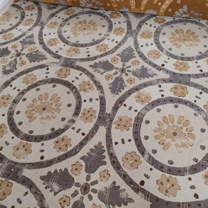 Könnte beinhalten: Beigefarbener Stoff mit einem sich wiederholenden Muster aus braunen Kreisen und floralen Designs. Die Kreise haben einen abgenutzten Look und sind mit Braun umrandet.