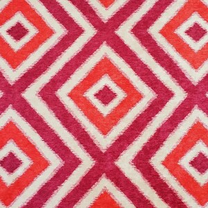 May include: A fabric with a geometric pattern of red and pink diamonds on a white background. The diamonds are outlined in white and have a subtle, textured look.