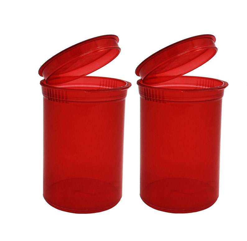 May include: Two red plastic pill bottles with lids open. The bottles are clear and have a textured surface.
