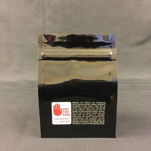 May include: Black mylar bag with a warning label that reads "Not for Kids" and includes an emergency contact number. The label has a red hand symbol and white text.