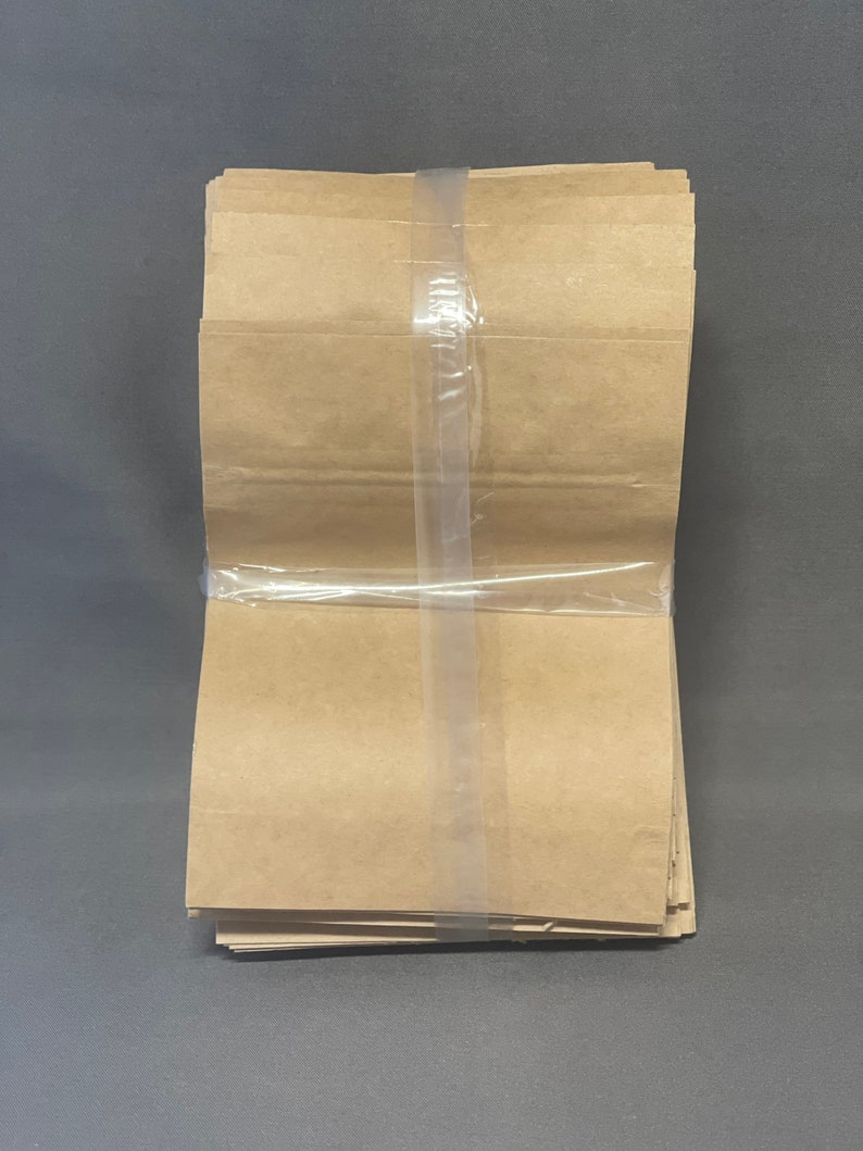 Peut inclure: Une pile de sacs en papier brun envelopp&eacute;s de plastique transparent.
