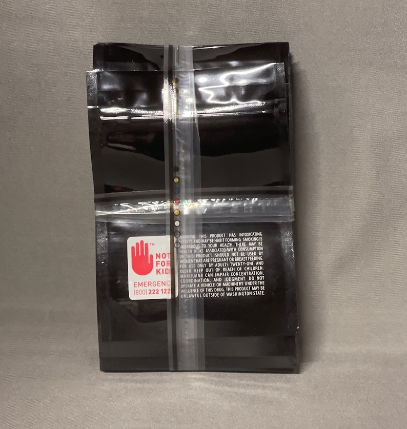 May include: A stack of black plastic bags with a warning label that reads "NOT FOR KID" and includes an emergency contact number. The label also includes a red hand with a stop sign.