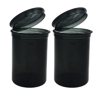 May include: Two black plastic pill containers with clear lids. The lids are open and the containers are empty.