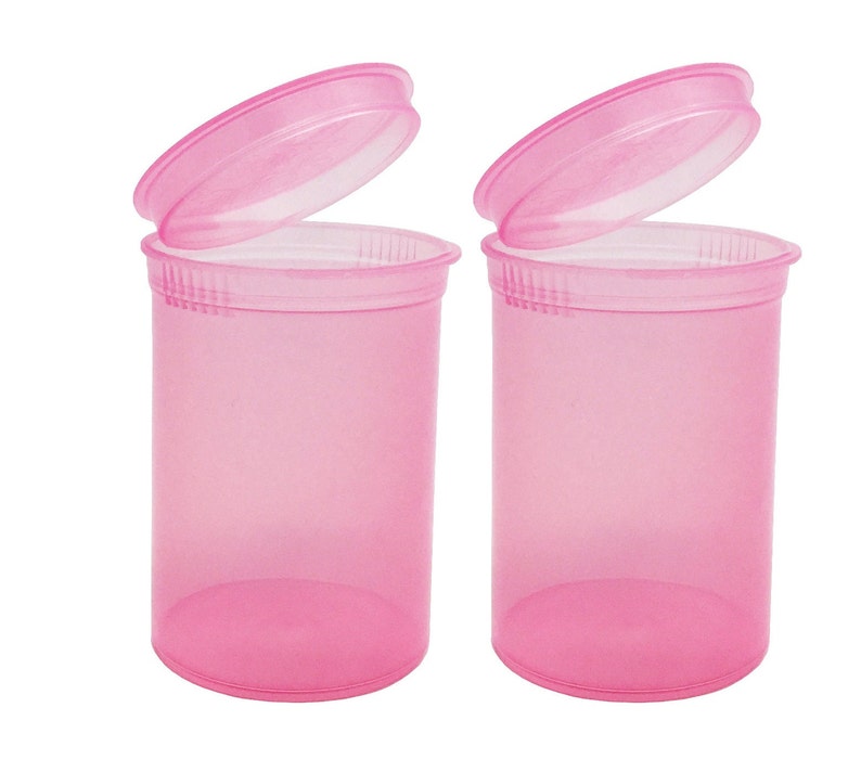 May include: Two pink plastic pill bottles with lids open. The bottles are translucent and have a smooth, rounded shape.