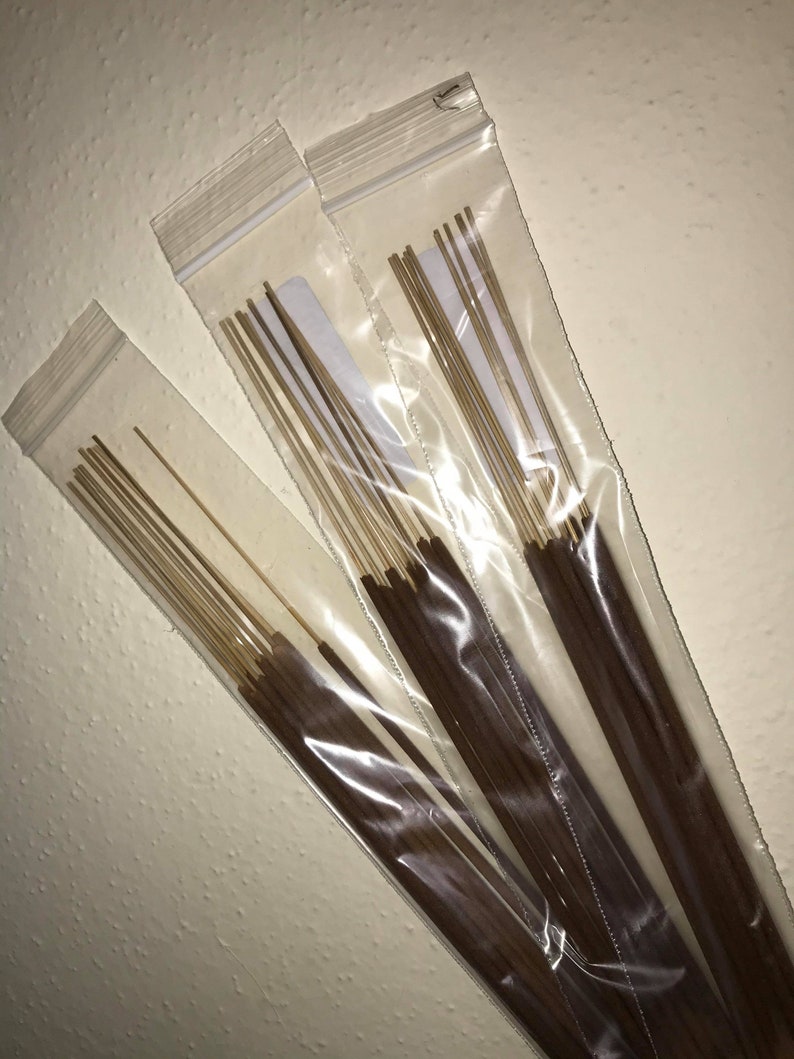 May include: Three packages of brown incense sticks in clear plastic bags. The sticks are bundled together and have a light brown color.