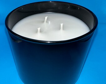 May include: A black ceramic candle holder with three white wicks and a white wax candle inside.