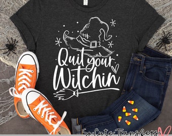 Puede incluir: Una camiseta gris oscuro con un gráfico blanco de un sombrero de bruja y el texto "Quit your Witchin". El gráfico también incluye una escoba y un corazón. La camiseta está colocada sobre una superficie blanca con un par de zapatillas de deporte naranjas y unos vaqueros azules.