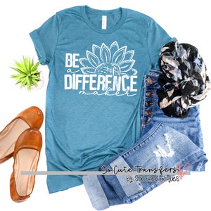 May include: A teal blue t-shirt with a white sunflower graphic and the text "Be a Difference Maker".