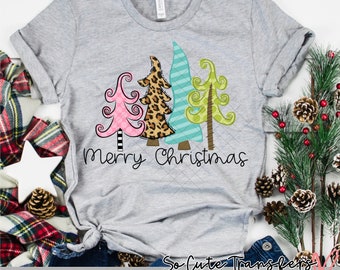 May include: A gray t-shirt with a design of three stylized Christmas trees. The trees are pink, leopard print, and green. The text "Merry Christmas" is printed below the trees.