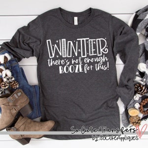 May include: A gray long-sleeved shirt with white text that reads "WINTER there's not enough BOOZE for this!" The shirt is on a white wooden surface. The text is in a playful, handwritten font.