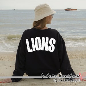 May include: Black sweatshirt with white distressed text that reads "LIONS" on the back.