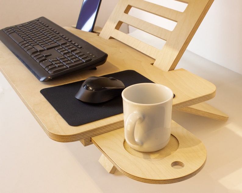 May include: A wooden laptop stand with a built-in keyboard tray, mouse pad, and cup holder. The stand is made of light wood and has a natural finish.