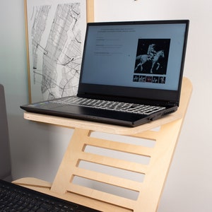 May include: A laptop computer with a black keyboard and a wooden laptop stand. The laptop is open and displaying a website with a picture of a person riding a horse.