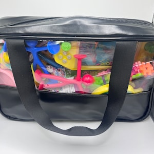 May include: A black zippered tote bag with a clear plastic window. The window shows a variety of colorful toys, including a blue and green fidget toy, a red and yellow toy, and a multi-colored toy.