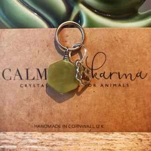 May include: A green jade stone charm with a silver paw print charm attached to a silver key ring. The charms are labeled "Calm Karma for Animals" and "Handmade in Cornwall U.K."