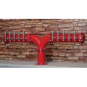 Könnte beinhalten: Ein roter Bierzapfhahn aus Metall mit 12 Zapfhähnen. Der Turm hat die Form eines Y und hat eine Basis, die an einer Wand befestigt ist.