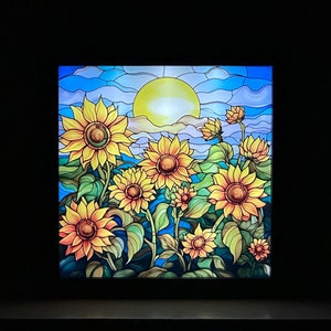 May include: A stained glass window depicting a sunny day with a field of sunflowers. The sunflowers are in various shades of yellow and orange with green leaves. The sun is a bright yellow circle in the sky.