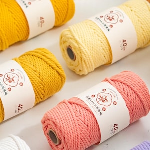 May include: A collection of ten spools of twisted cotton cord in various colours including yellow, blue, pink, purple, cream, and orange. Each spool features a white paper band with a circular logo and the text 4.0mm printed on the front.