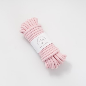 May include: A bundle of light pink macrame cord with a white label wrapped around it. The label has the text "SHEWEAVE-MACRAME" and other text in a different language. The cord is 8mm thick.