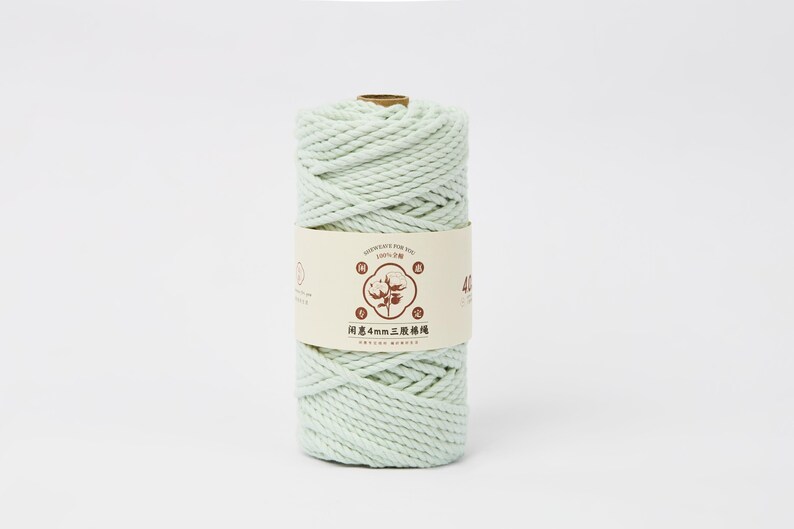 May include: A spool of light mint green cotton cord wrapped in a cylindrical shape. A beige paper label is wrapped around the center, featuring a brown graphic of a cotton plant, Chinese text, and the number 40, indicating a 4mm thickness.