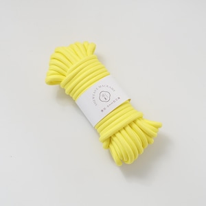 May include: A tightly coiled bundle of bright yellow macrame cord. A white label wrapped around the cord displays the text "SHEWEAVE-MACRAME" and other text in a foreign language. The cord appears to be approximately 8mm in diameter.