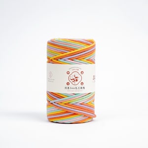 May include: A colorful spool of 3mm cotton rope in shades of orange, yellow, pink, green, and purple. The rope is wrapped around itself and has a white label with Chinese text and a cotton flower logo.