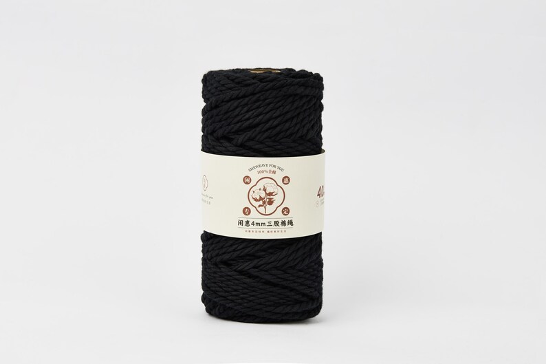 May include: A cylindrical spool of black cotton cord wrapped in a cream-colored paper label. The label features a central illustration of a cotton plant, Chinese text, and the specific measurement of 4mm printed clearly on the front surface.