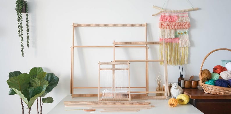 May include: A collection of light-colored wooden weaving looms in various sizes, featuring notched top and bottom bars for tensioning warp threads. The set includes several rectangular frames and flat wooden components arranged on a surface.