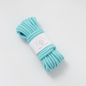 May include: A bundle of light blue macrame cord. The cord is wrapped with a white label that has black text and a logo. The cord appears to be 8mm in diameter. The cord is tightly wound and ready for crafting.