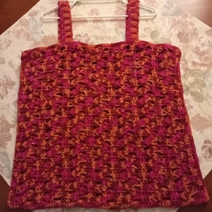 May include: A crocheted tank top with a geometric pattern in shades of pink and orange.