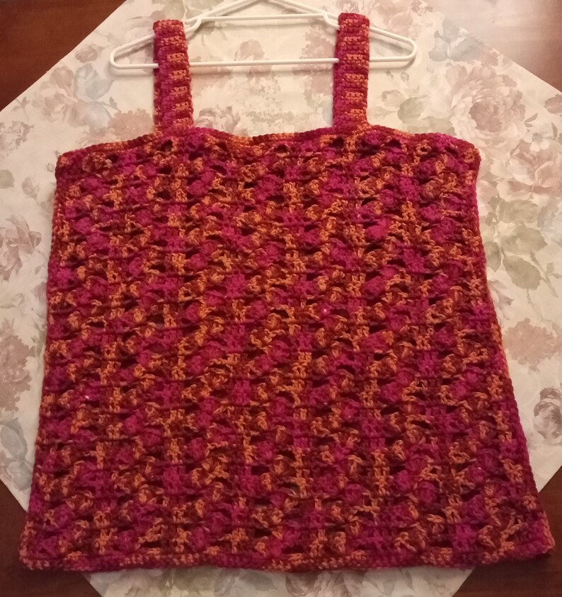 May include: A crocheted tank top with a geometric pattern in shades of pink and orange.