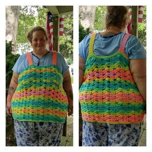May include: A rainbow crochet top with a wide, open neckline and a loose, flowy fit. The top is made with a colorful yarn that creates a striped pattern. The top is worn over a blue shirt and floral pants.